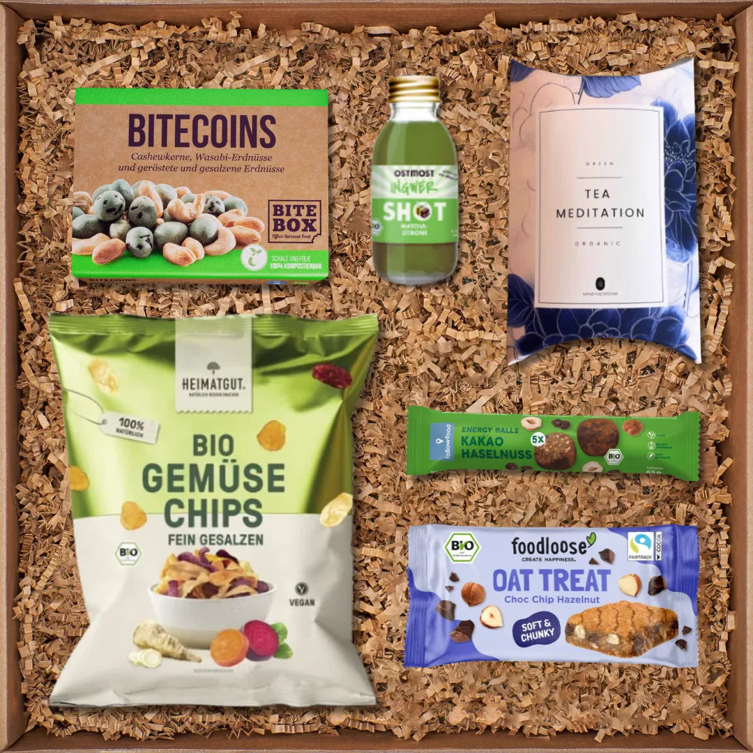 Geschenkbox mit Bitecoins Nussmischung, Ingwer Shot, Green Tea Meditation, Bio-Gemüsechips, Energy Balls und Oat Treat Riegel.