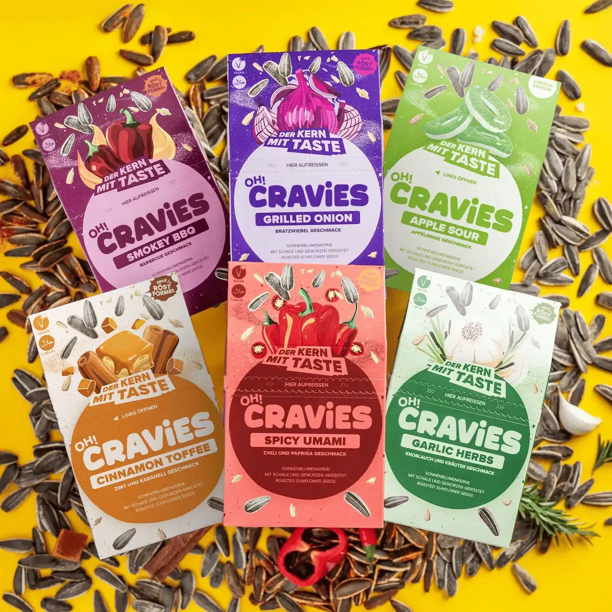 Sechs bunte Cravies-Sonnenblumenkern-Snackpackungen mit verschiedenen Geschmacksrichtungen auf gelbem Hintergrund.