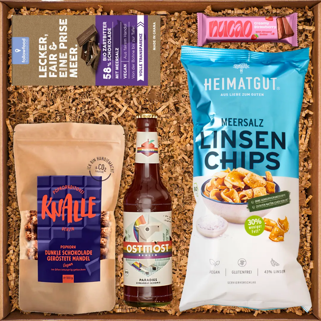 Geschenkbox mit dunkler Schokolade, Linsenchips, Popcorn mit Mandeln, Getränk und Erdbeer-Schokoriegel.