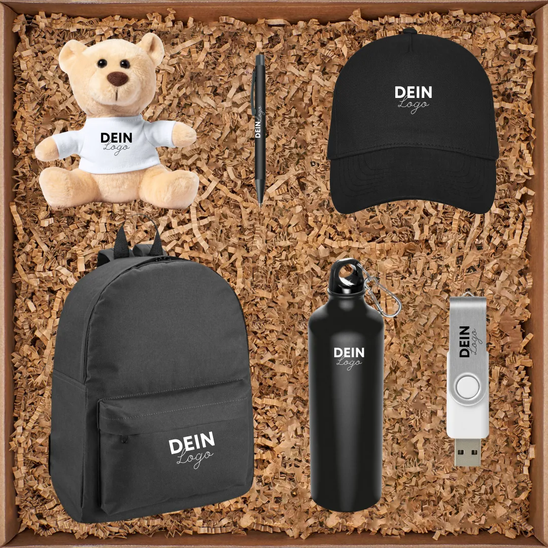 Offene Geschenkbox mit gebrandetem Merch: Teddy im T-Shirt, Cap, Rucksack, Trinkflasche, USB-Stick und Kugelschreiber, alle mit dem Aufdruck „Dein Logo“.