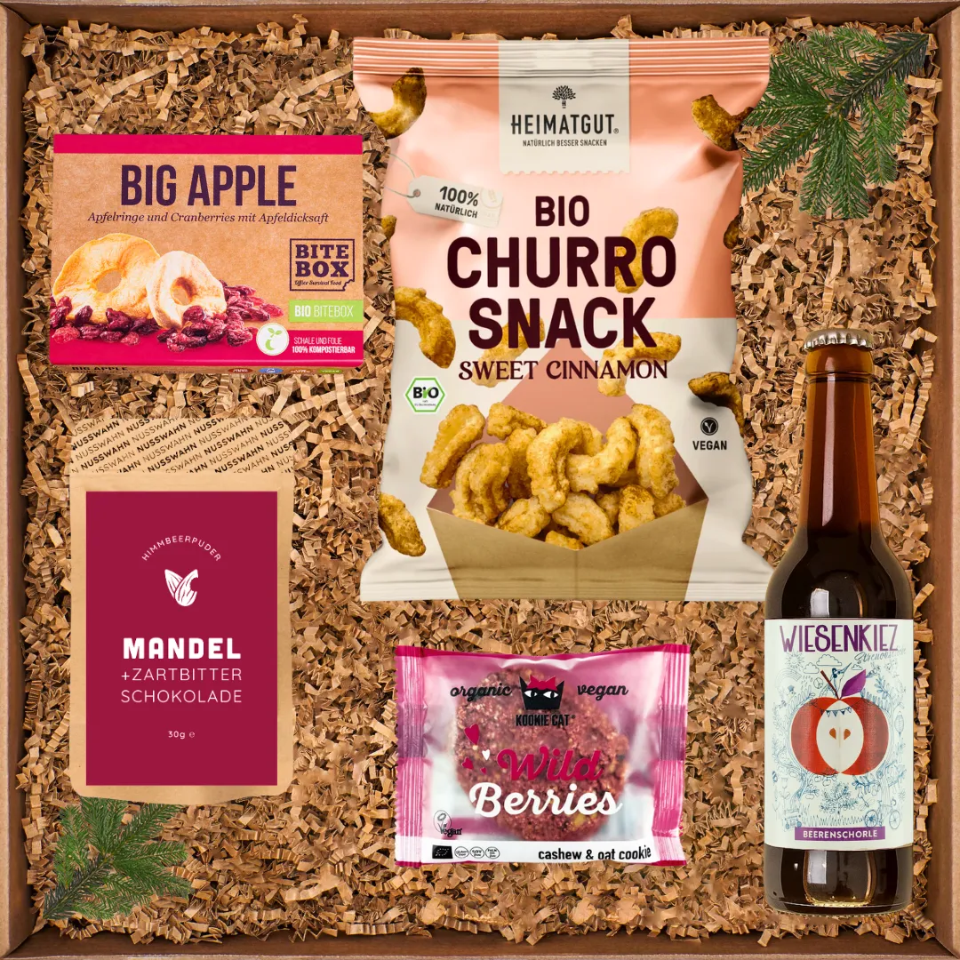 Geschenkkarton mit Bio-Snacks: Big Apple Trockenfrüchte, Bio-Churro-Snack, Mandelschokolade, Wild Berries und Beerenschorle.