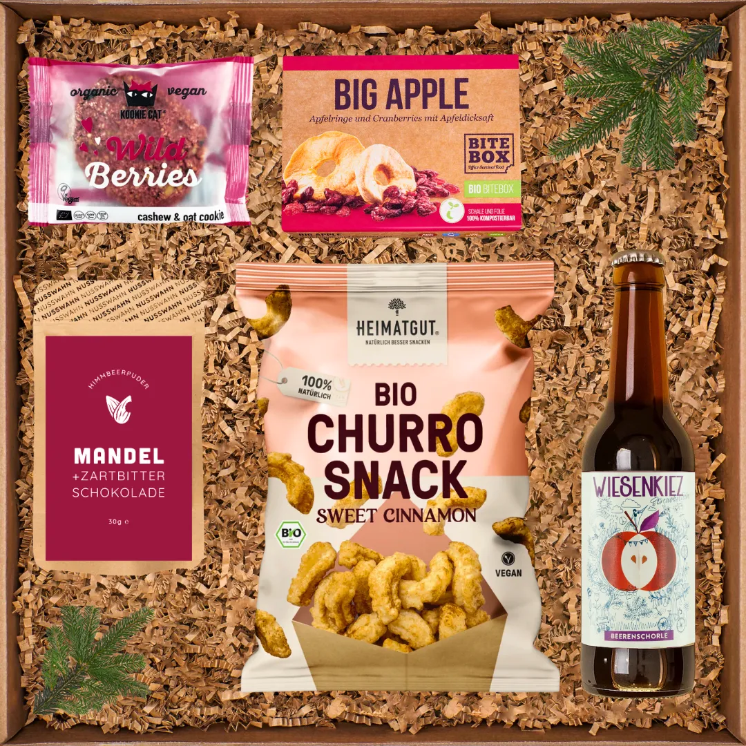 Geschenkbox mit Bio-Churro-Snack, Big Apple Trockenfrüchten, Schokolade, Wild Berries Keks und Beerenschorle.